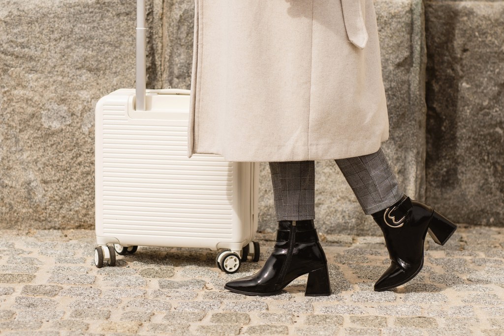 Digital nomad in chic travel outfit with minimalist carry-on suitcase, representing the art of packing for a workation and modern remote work life.