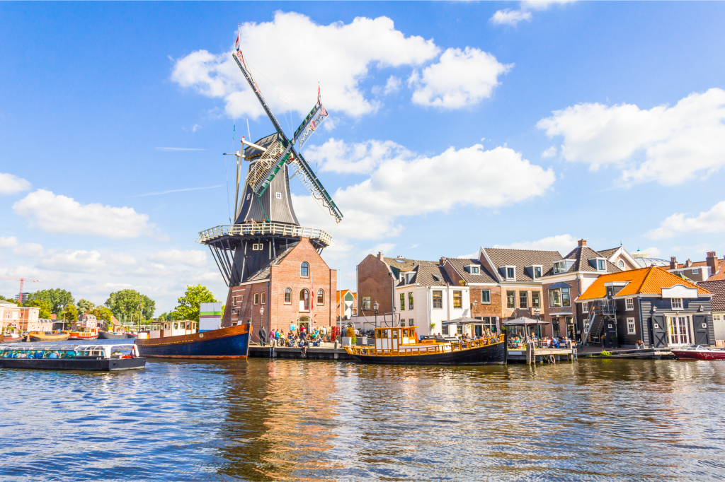 Canal view with traditional windmill and boats in the Netherlands on a sunny day — scene symbolizing the bleisure trip that almost happened.