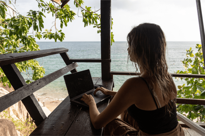 Woman working remotely with a laptop while traveling, balancing work and relaxation during a stay-workation day.